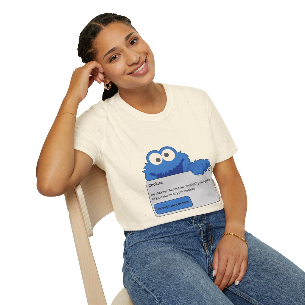 A person wearing a sand colored t-shirt with a Cookie Monster design, sitting on a chair.